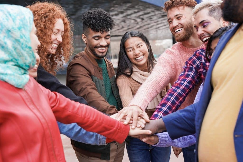 Group of young multiracial people stacking hands outdoor